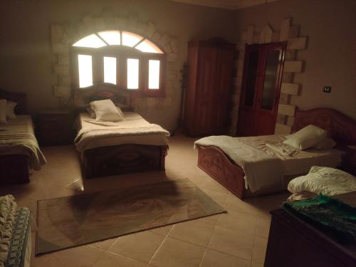 a room with two beds and a window at Panta Lodge Siwa بنتا لودج سيوة in Siwa