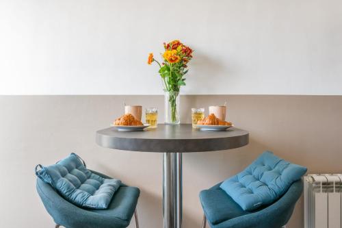 einen Tisch mit zwei blauen Stühlen und eine Vase mit Blumen in der Unterkunft Modern and colourful apartment with balcony - Montpellier - Welkeys in Montpellier