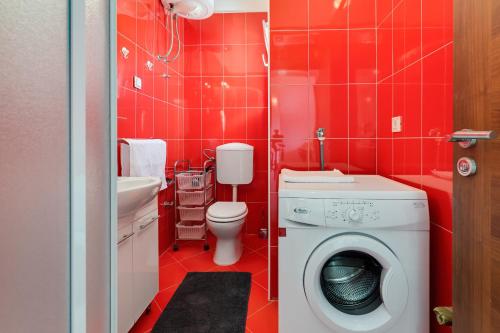 a red bathroom with a washing machine in it at Apartman Strmota s bazenom i jakuzijem in Sveti Filip i Jakov