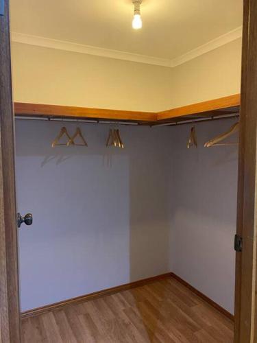 a room with a white wall with hangers and a door at Comfortable Home in Camden Park in Plympton