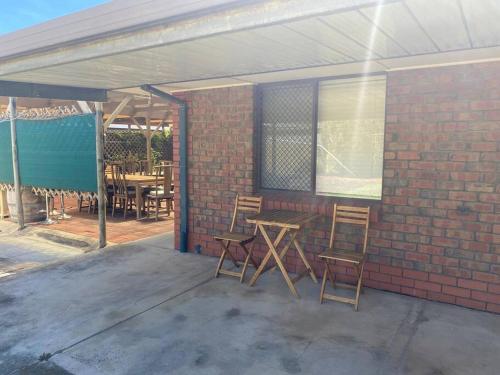 a patio with chairs and a table and a brick wall at Comfortable Home in Camden Park in Plympton