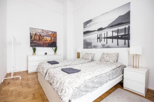 a white bedroom with a bed and a picture on the wall at Elegant Apartment in Super Central Location in Budapest