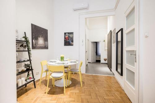 a dining room with a table and yellow chairs at Elegant Apartment in Super Central Location in Budapest