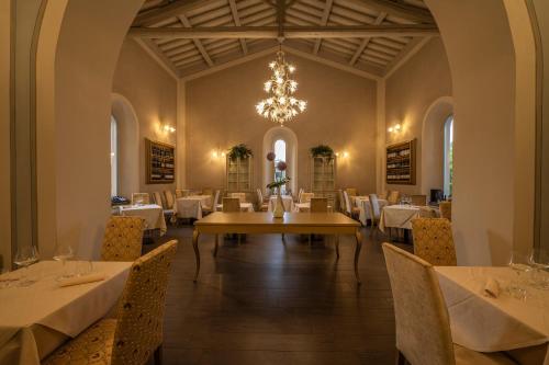 uma sala de jantar com mesas e cadeiras e um lustre em Hotel Palazzo San Lorenzo & Spa em Colle Val D'Elsa
