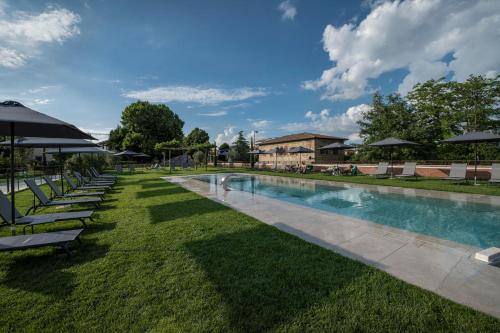 a swimming pool with lawn chairs and umbrellas at Hotel Palazzo San Lorenzo & Spa in Colle Val D'Elsa