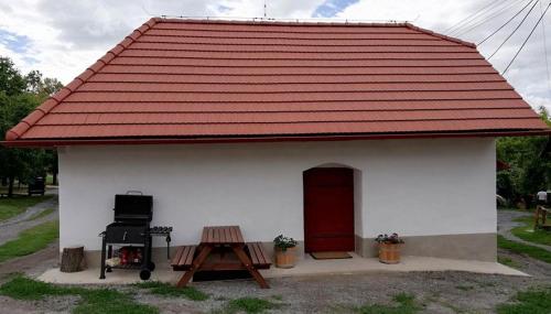 a small white building with a red roof and a grill at Chyžka Stará Hora in Sebechleby