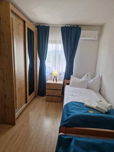 a bedroom with a bed with blue sheets and a window at Apartmani Leburic in Prnjavor