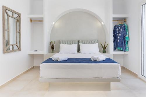 a white bedroom with a large bed with two towels at Naxos Leisure in Agios Prokopios