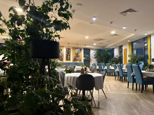 Restoran Leburic في Prnjavor: غرفة طعام بها طاولات وكراسي ونباتات