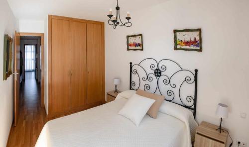 a bedroom with a white bed and a wooden door at El rincón del 12 in Pontevedra