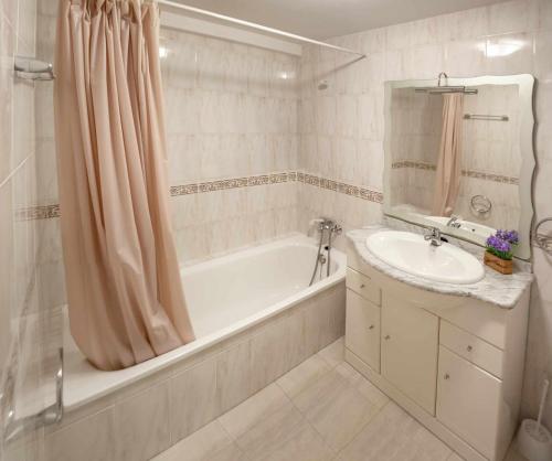 een witte badkamer met een bad en een wastafel bij El rincón del 12 in Pontevedra
