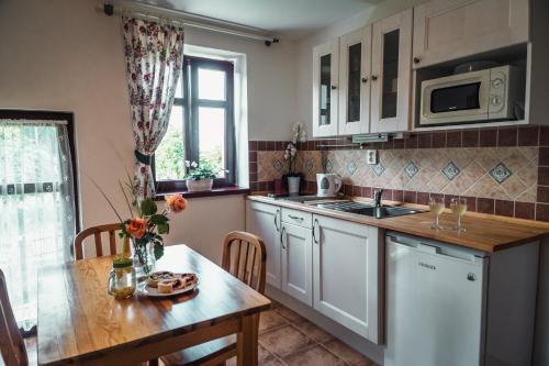 a kitchen with white cabinets and a table and a sink at Penzion Apartmány Hetlín in Černíny