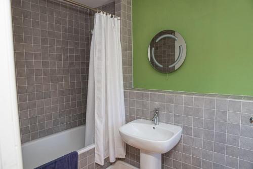 a bathroom with a sink and a tub and a mirror at White Horses a large family home in Bantham South Devon with fantastic sea views in Bigbury on Sea