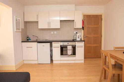 a kitchen with white appliances and a wooden floor at White Horses a large family home in Bantham South Devon with fantastic sea views in Bantham