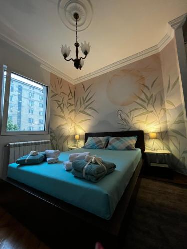 a bedroom with a bed with blue sheets and a chandelier at Apartman Sasha 1 in Sajmište