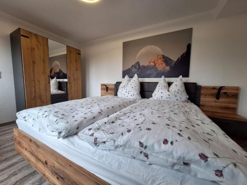 - une chambre avec un grand lit blanc orné de fleurs dans l'établissement Haus Silbertann, à Schönau am Königssee