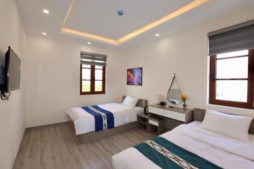 a hotel room with two beds and a desk at Rova 105 Hotel in Phu Quoc