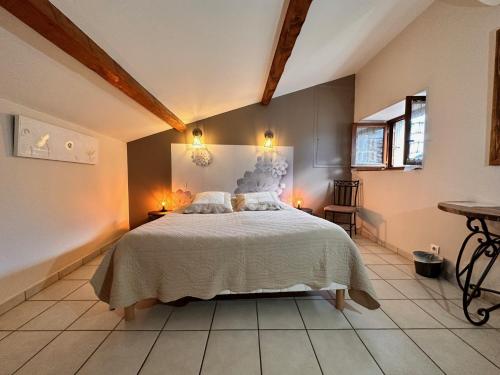 a bedroom with a large bed and two lights on the wall at Chambres d'hôtes les Clapas in Chauzon