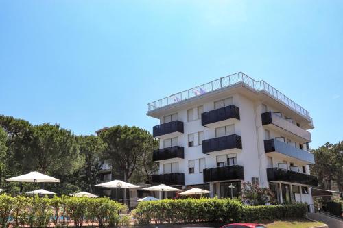 ein weißes Gebäude mit Balkonen und Sonnenschirmen in der Unterkunft Hotel Eden in Lignano Sabbiadoro