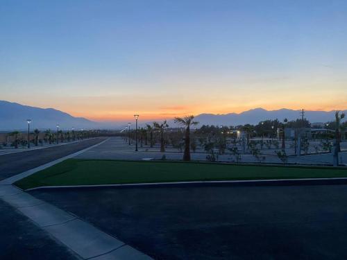 an empty street with palm trees and a sunset at RV51-Lot-Paradise RV Park in Desert Hot Springs
