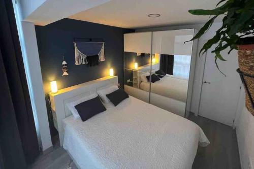una camera con letto bianco e specchio di Apartamento AGUA con Jacuzzi y terraza a Las Palmas de Gran Canaria