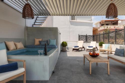 um pátio exterior com uma banheira de hidromassagem e cadeiras em Ierapetra’s Mosque House em Lerápetra