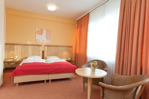 Schlafzimmer mit einem roten Bett und einem Tisch in der Unterkunft Hotel Imperial in Hamburg