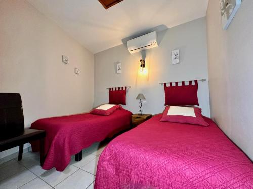 two beds in a room with red sheets at Chambres d'hôtes les Clapas in Chauzon