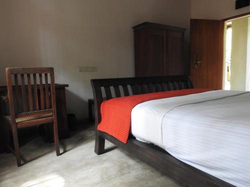 a bedroom with a bed and a wooden chair at Mannankulam Villa in Akkaraipattu