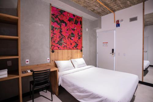 um quarto com uma cama e uma secretária com uma cadeira em CAMPOS DE HOLAMBRA INN em Paranapanema