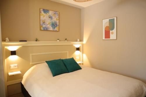 ein Schlafzimmer mit einem weißen Bett und einem grünen Kissen in der Unterkunft L'Escapade Tropicale in Bourbourg