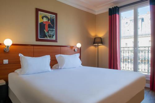 een slaapkamer met een groot wit bed en een raam bij Hôtel Coypel by Magna Arbor in Parijs