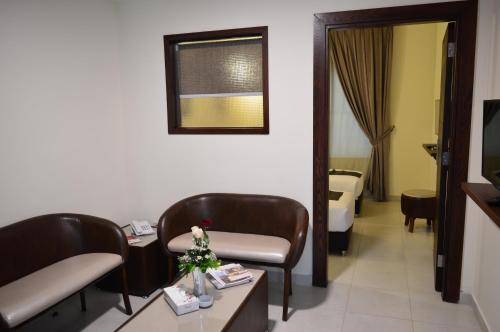 a room with two chairs and a table and a bed at Ream Hotel Amman in Amman