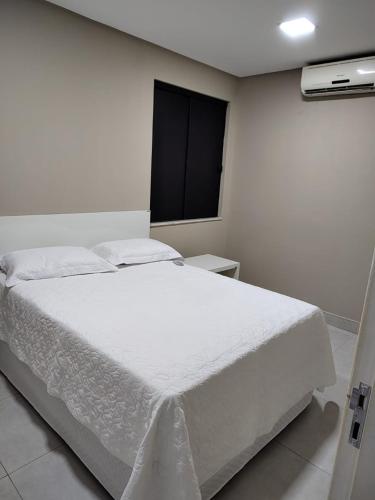 a white bed in a room with a window at Apartamento 2 Quartos - 5 minutos do São João de Petrolina in Petrolina