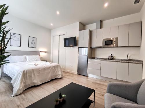 a white bedroom with a bed and a kitchen at EDIFICIO DUQUE in Málaga