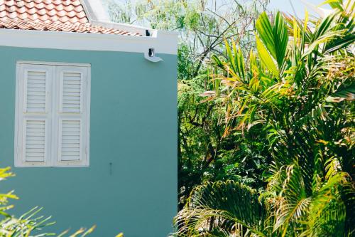 a white window on the side of a house with trees at Pietermaai Oasis in Willemstad