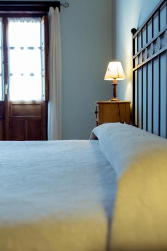 a bedroom with a bed with a lamp and a window at El Molino de Bonaco in San Vicente de la Barquera