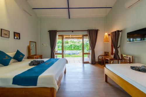 a bedroom with two beds and a sliding glass door at Khu Nghỉ Dưỡng Green Bungalow Phu Quoc in Phu Quoc