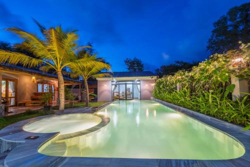 a swimming pool in the backyard of a house with palm trees at Khu Nghỉ Dưỡng Green Bungalow Phu Quoc in Phu Quoc
