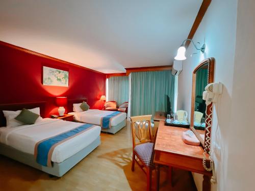 Pokój hotelowy z 2 łóżkami i biurkiem w obiekcie Ubonburi Hotel w mieście Ubon Ratchathani