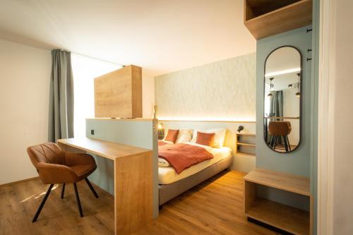 1 dormitorio con cama, escritorio y espejo en Hotel zum Löwen en Weißenhorn