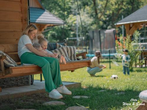 a woman holding a child sitting on a swing at Drevenice Wars & Sawa in Oščadnica