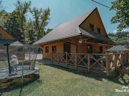 a large wooden house with a girl standing in front of it at Drevenice Wars & Sawa in Oščadnica
