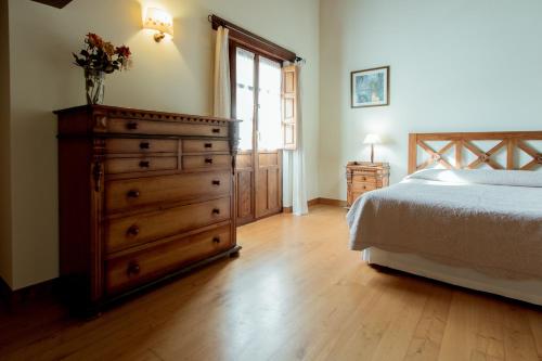 a bedroom with a dresser and a bed and a window at El Molino de Bonaco in San Vicente de la Barquera