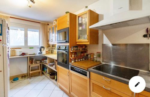 a kitchen with wooden cabinets and a stove top oven at 2 CHAMBRES B&B PRÈS DE L'AÉROPORT ET DU MEETT in Blagnac