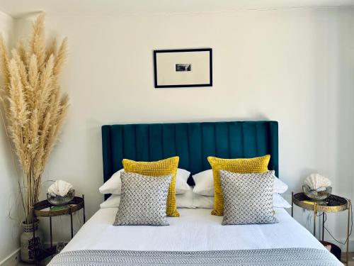 a bedroom with a bed with yellow and white pillows at Beautiful Beach House in Littlestone-on-Sea