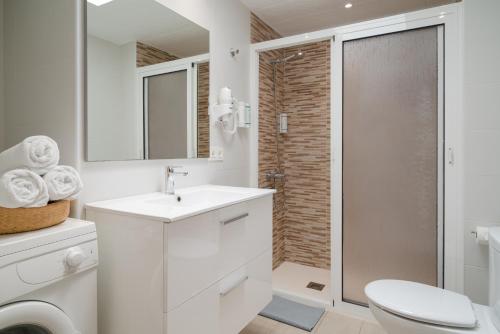 a white bathroom with a toilet and a sink at Sabbia Suites Pleamar in Puerto del Carmen