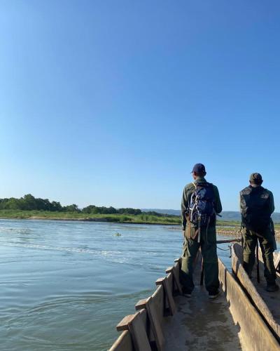 two men walking over a bridge over a river at Happy Lemon Tree lodge in Sauraha