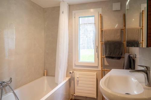 ein Bad mit einer Badewanne, einem Waschbecken und einem Fenster in der Unterkunft Chez Domi et Michou in Zermatt