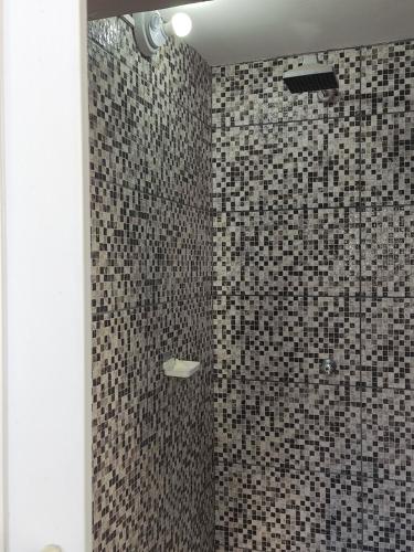 a bathroom with a shower with black and white tiles at Parada 86 Hostel in Sao Paulo